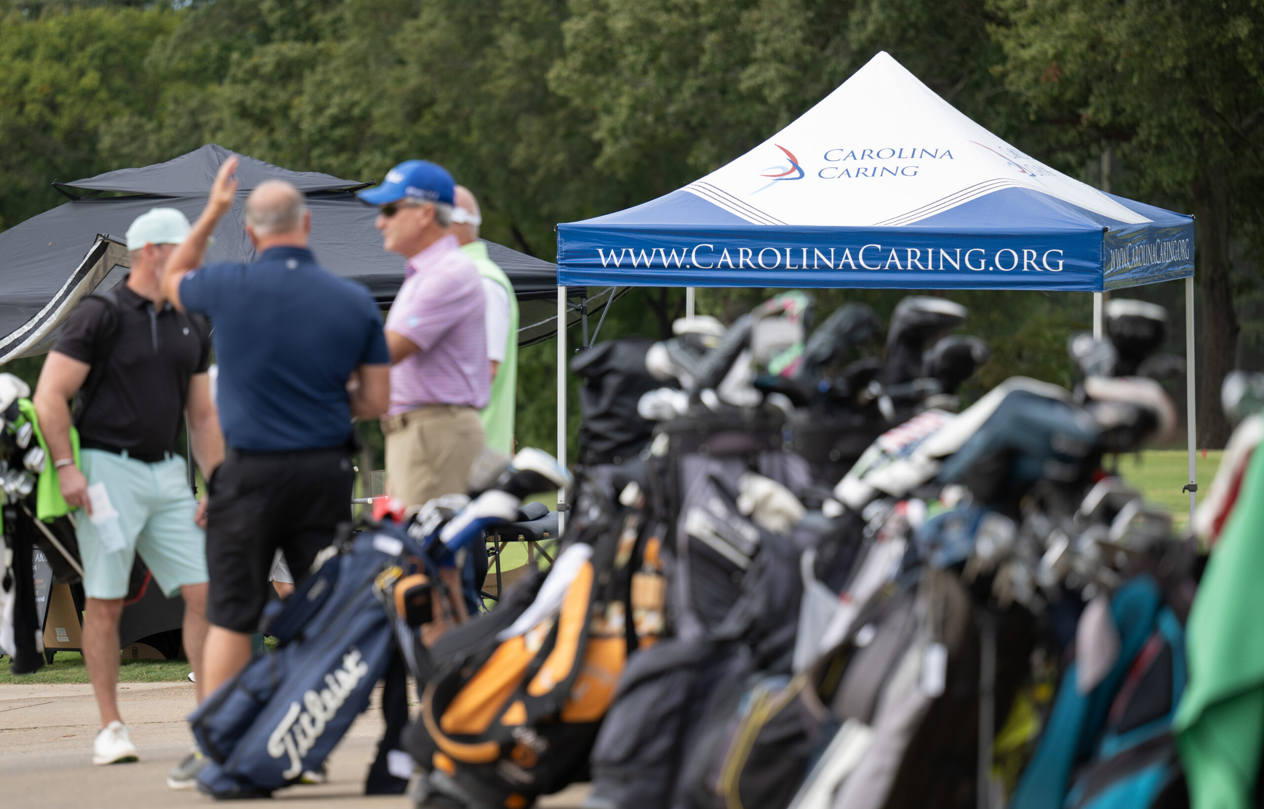 Golfers gather in front of Carolina Caring tent during 2026 Friends Fore Hospice Golf Tournament